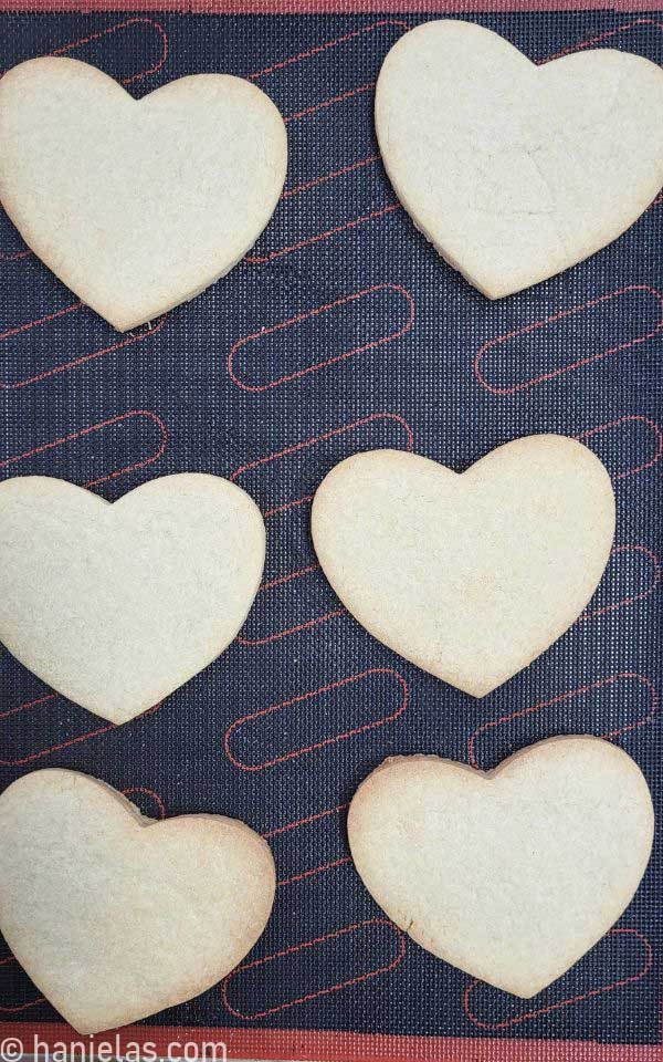 Baked cookies on a baking sheet, lined with a perforated mat.