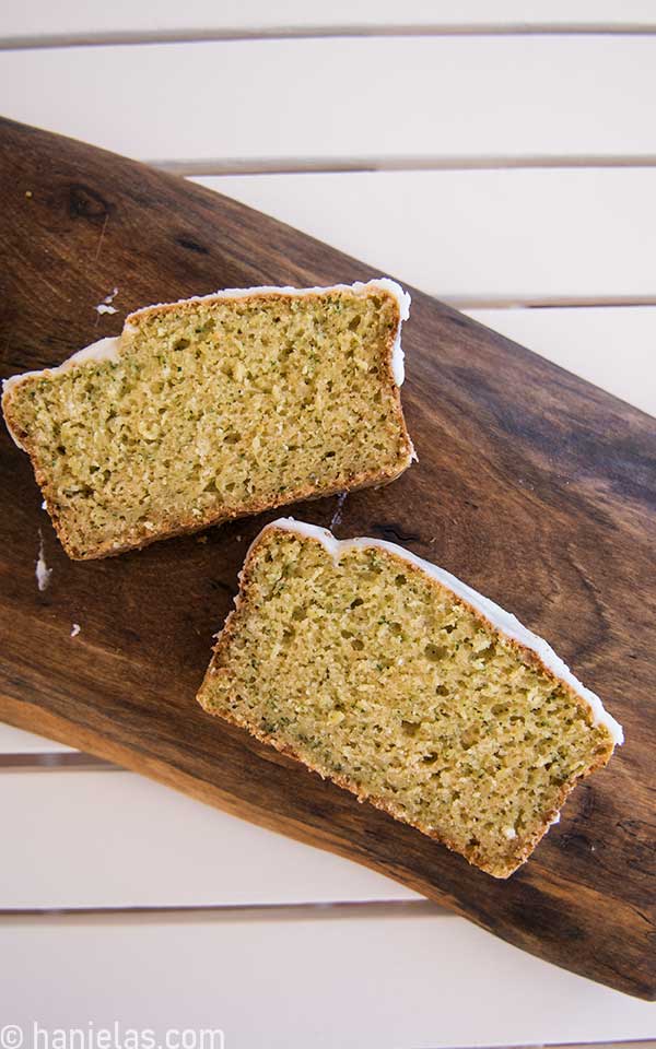 A view from above, a wooden cutting board with two slices of bread with white glaze.