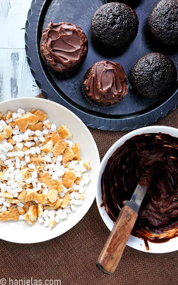 Bowls with chocolate ganache and crushed cookies and marshmallows.