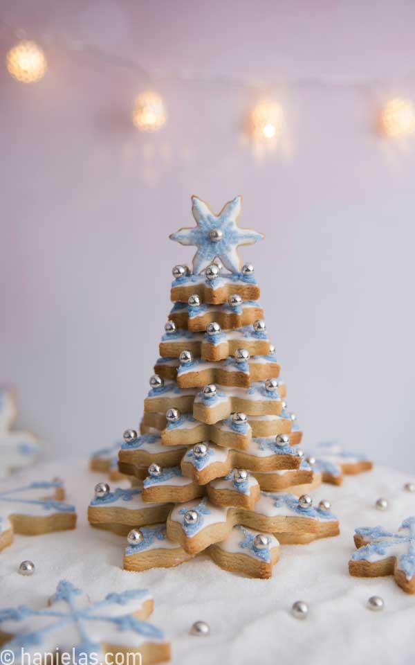 Tree made from stacked decorated cookies in front of a blurry background.