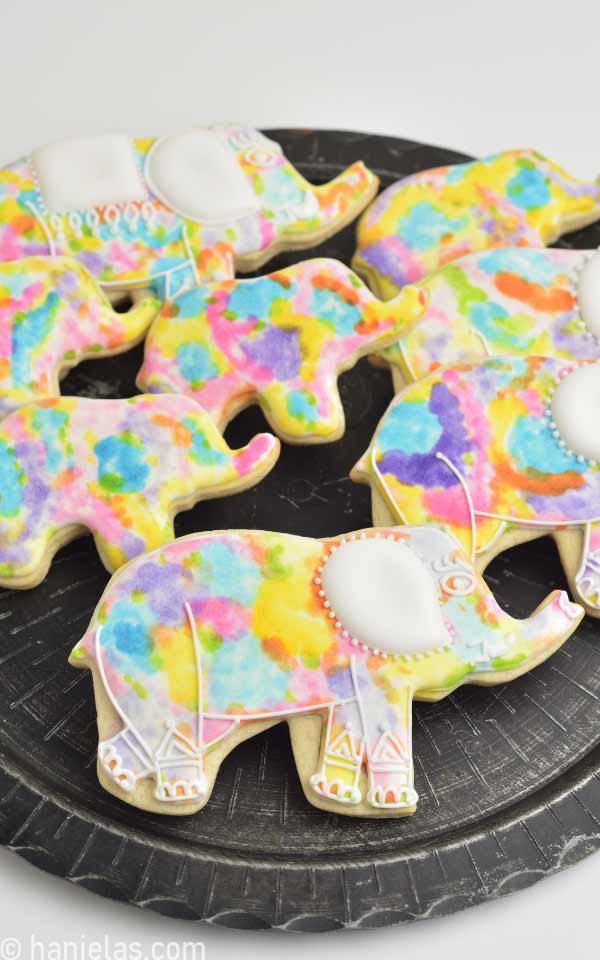 Decorated sugar cookies on a black plate.