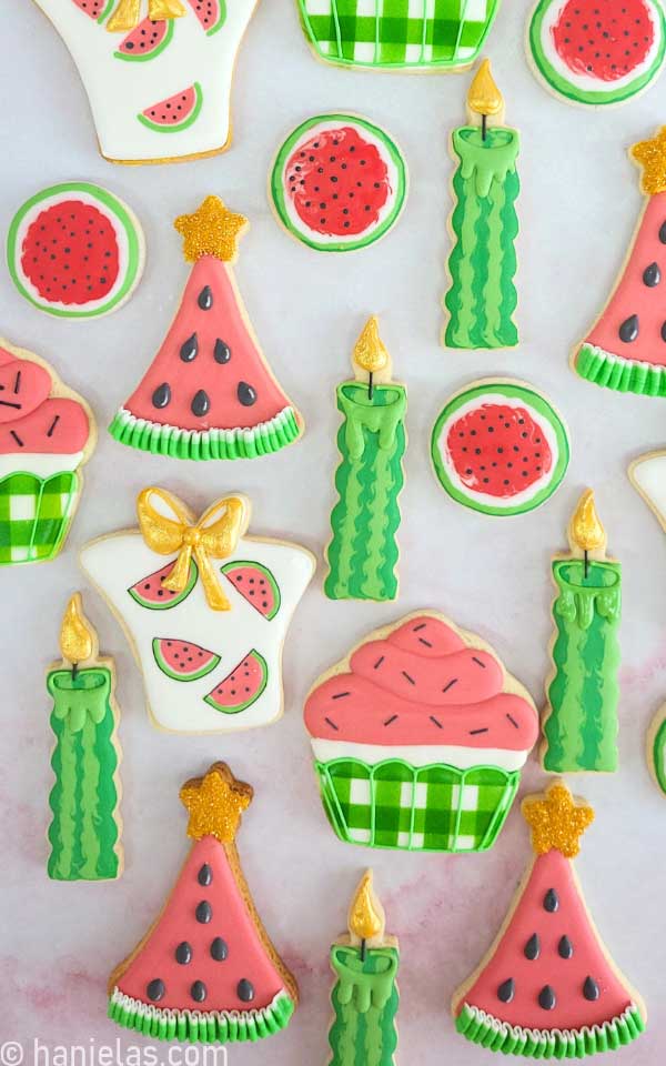 Cupcake, candle, present, party hat and a round cookie decorated with watermelon designs, using royal icing.