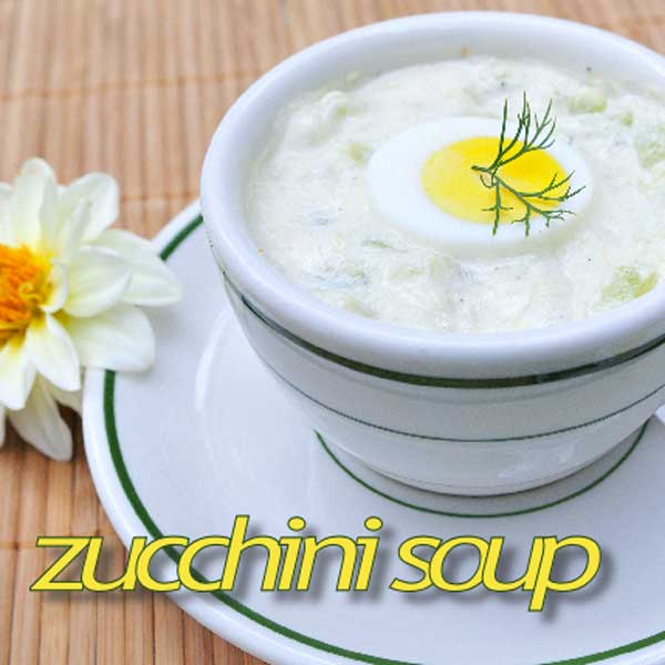 Soup in a small cup with a slice of hard-boiled egg on the top.