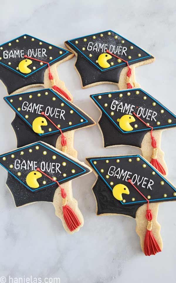 Six decorated cookies, displayed on a marble slab.