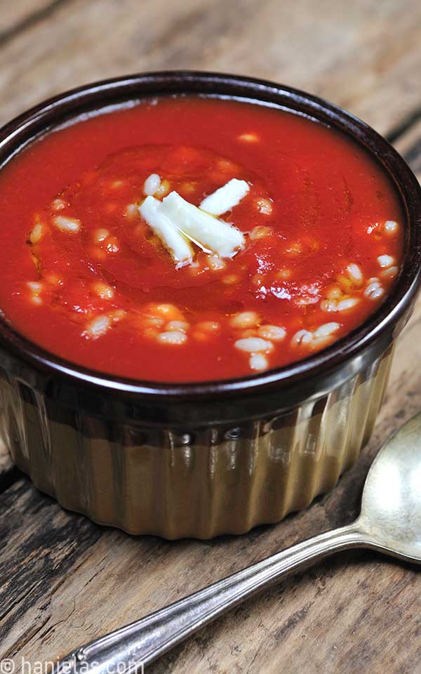 Small pottery dish with tomato soup and barley.