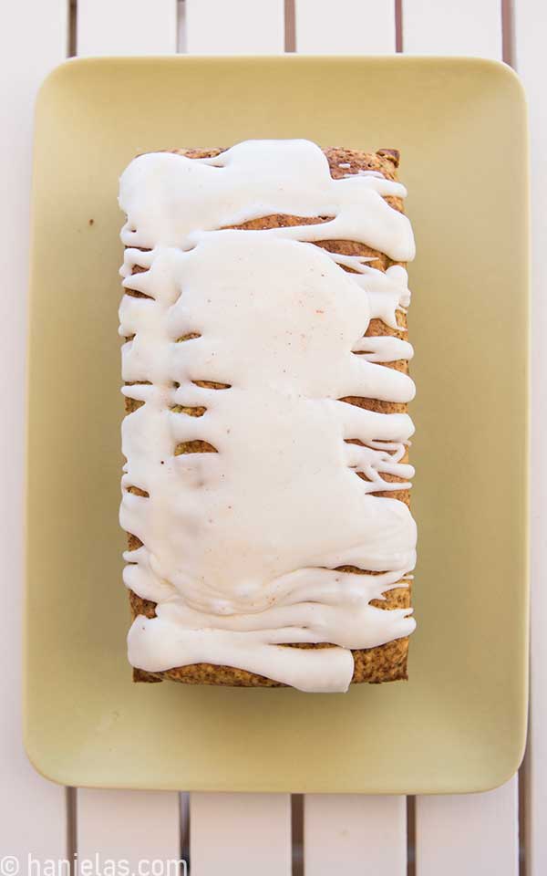 A light green plate with a loaf of bread glazed with white glaze.