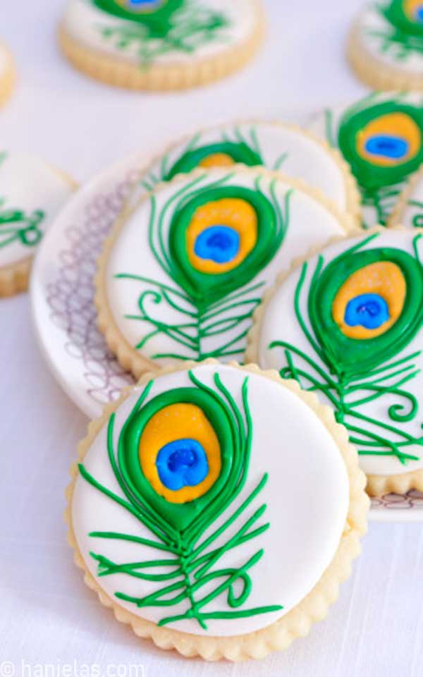 Round cookies iced with white icing and green peacock feather.