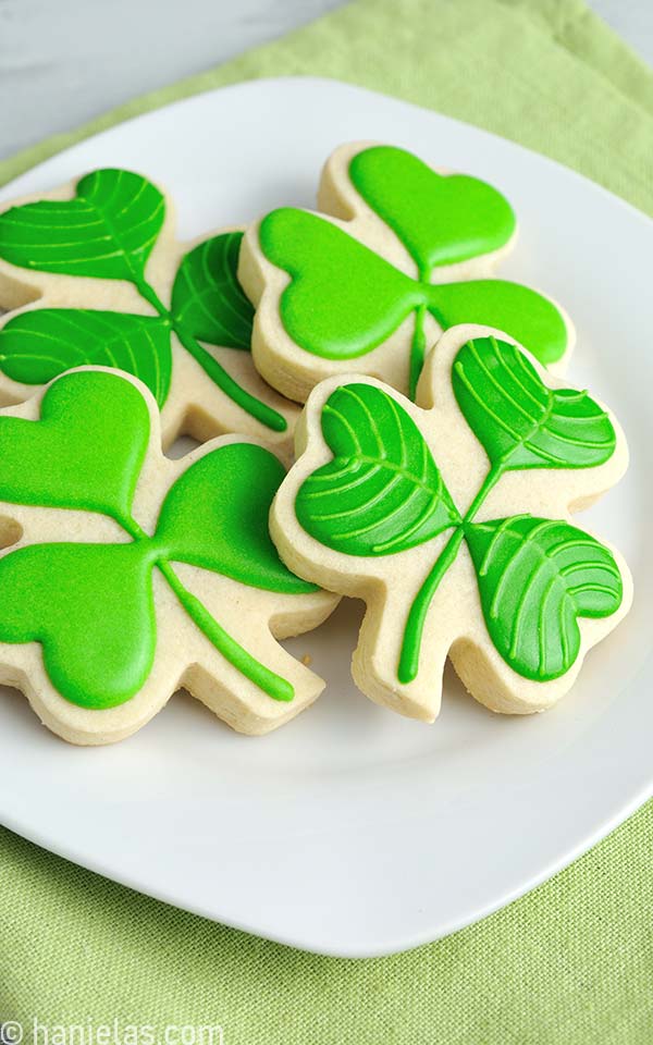 Decorated cookies in a shaped of of a leaf on a white plate.