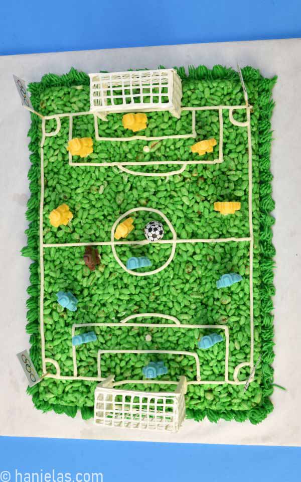 A view from above showing green no bake cereal soccer field cake with white chocolate goals and chocolate LEGO players.