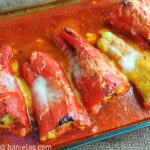 Glass casserole dish with roasted stuffed pepper in tomato sauce.