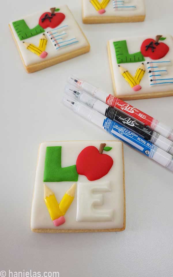 Decorated cookies with royal icing and three edible markers on the side.