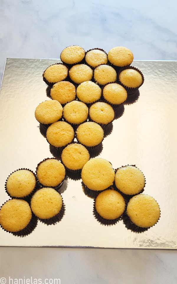 Undecorated mini cupcakes on a silver cake board.