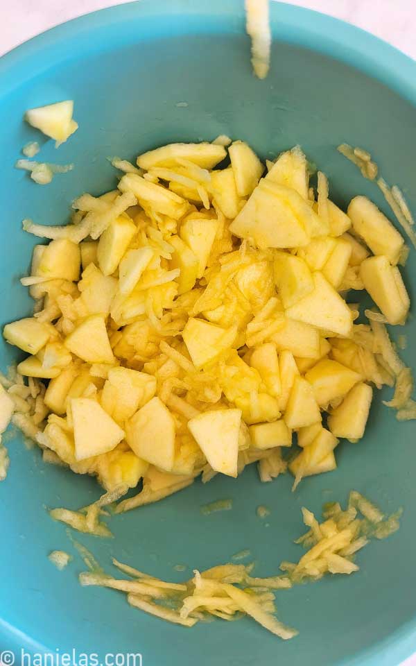 Teal mixing bowl with sliced and grated apples.