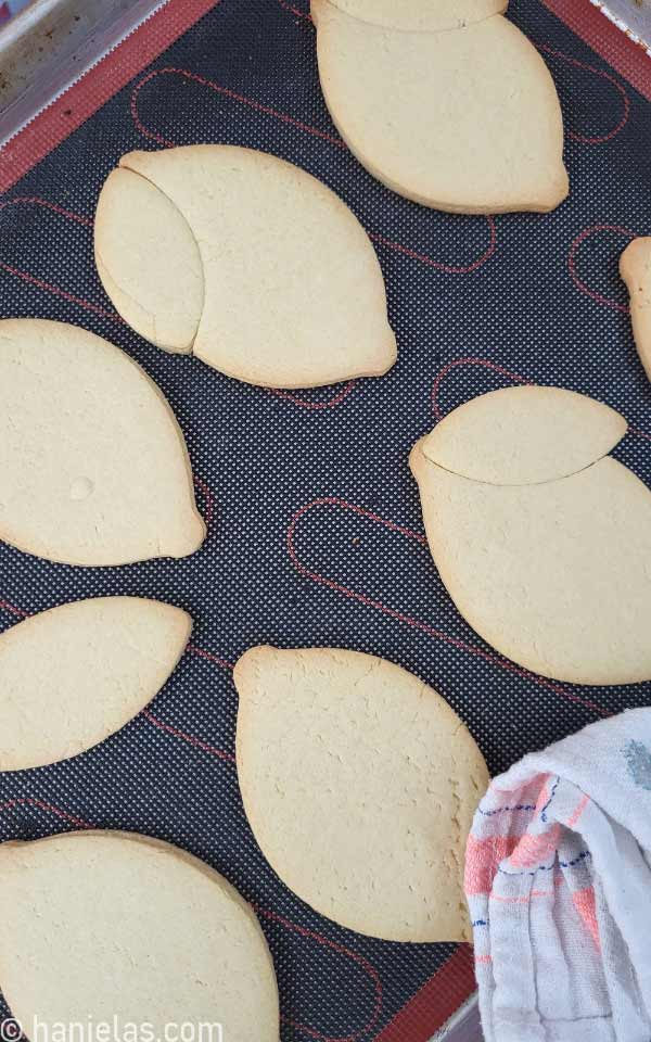 Baked, undecorated cookies on a baking sheet lined with a perforated mat.