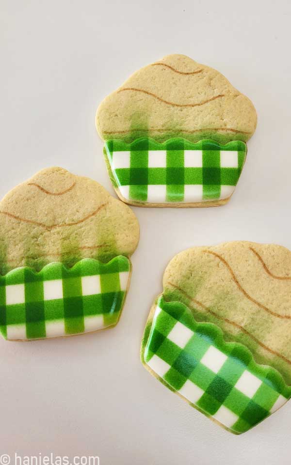 Three cupcake cookies with airbrushed green gingham liners.