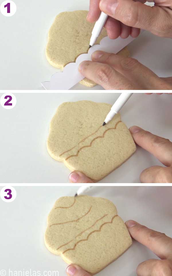 Hand-holding an edible marker, drawing guides onto a cookie.