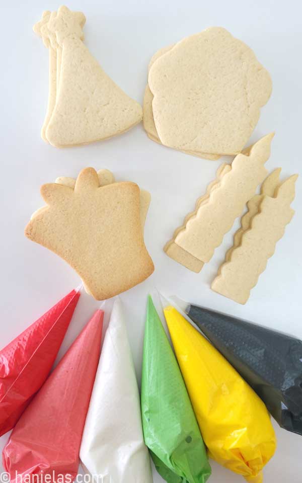 Undecorated cookies and piping bags with colored royal icing.