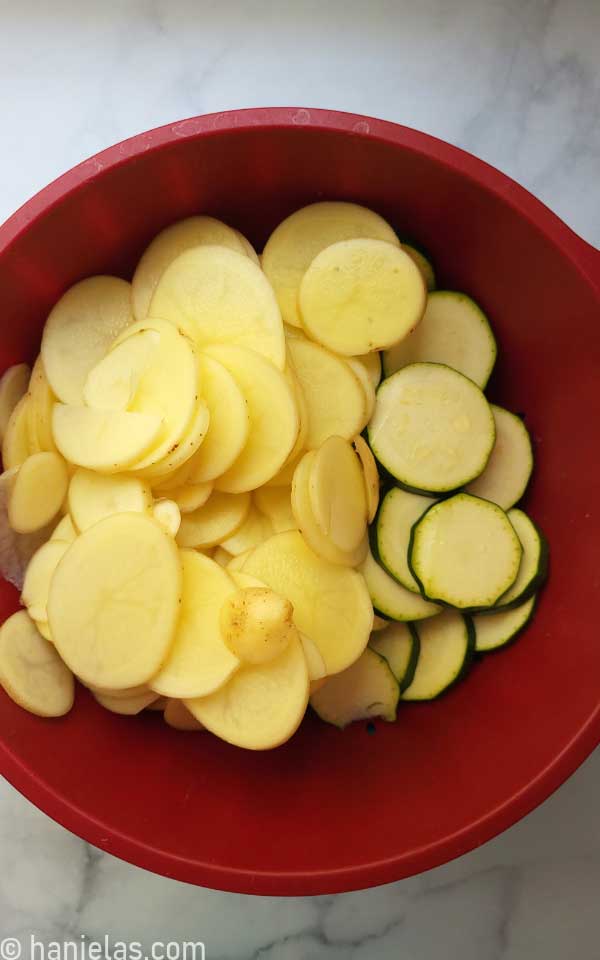 Bowl with sliced potatoes and zucchini.