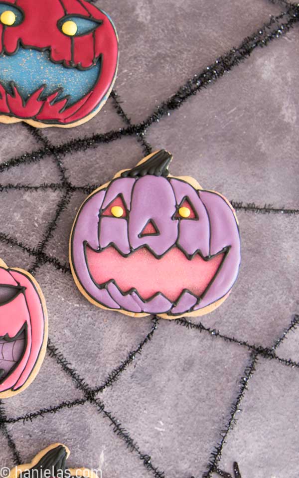 Pumpkin cookie decorated with royal icing to make look like jack-o'-lantern.