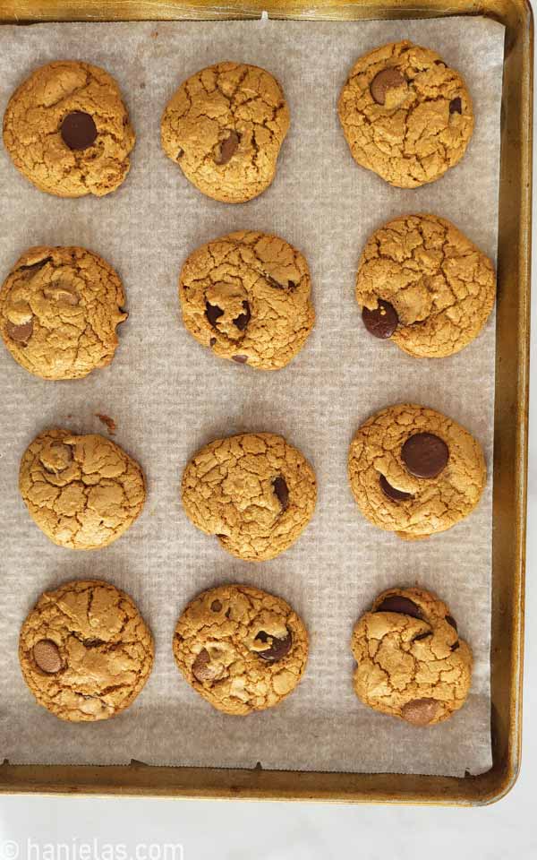 A baking sheet lined with white parchment paper with baked cookies.