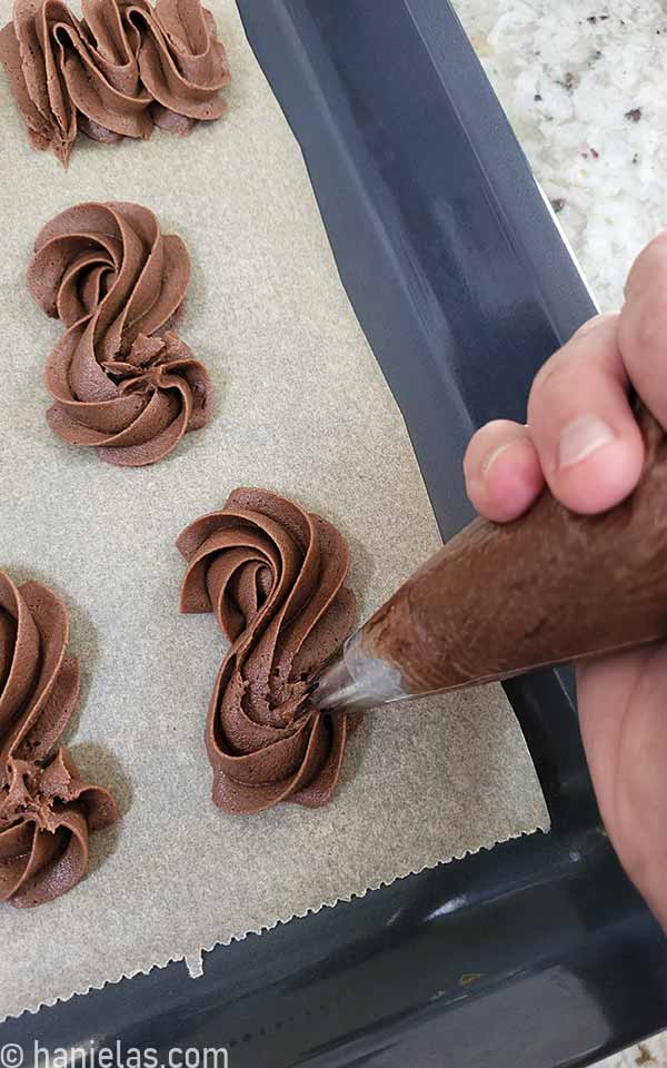 Hand holding a piping bag filled with chocolate cookie dough.