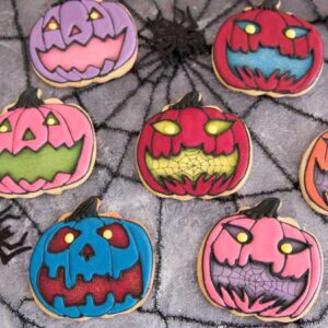 Cookies in a shape of a pumpkin decorated with royal icing.