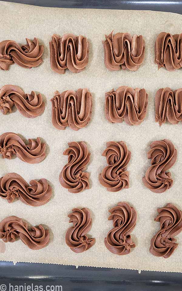 Unbaked piped chocolate cookie on a baking sheet.