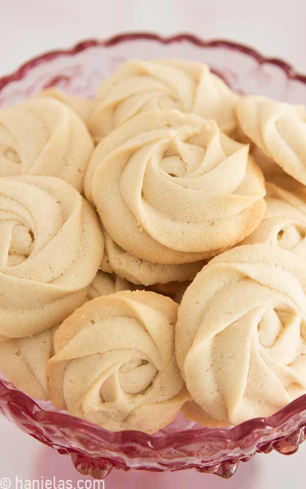 Cookies with lightly golden edges in a pink glass bowl.