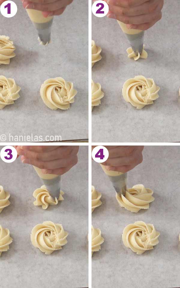 A hand holding a piping bag, piping swirls of cookie dough onto a baking sheet.