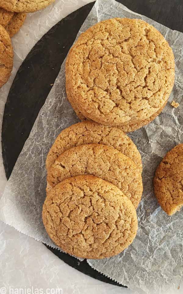 Stacked baked cookies on a black slate tray.