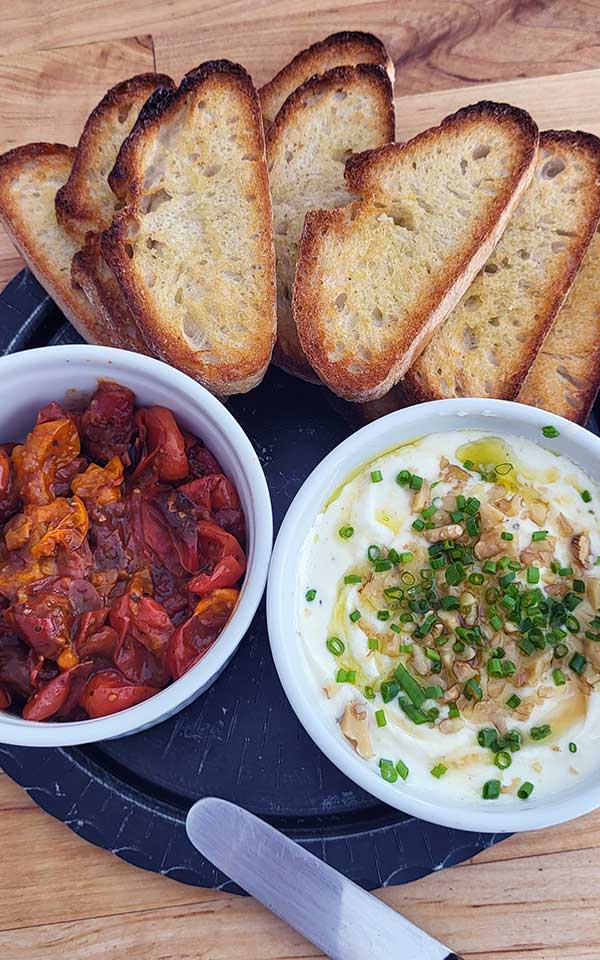 A close-up of roasted tomatoes whipped white dip.