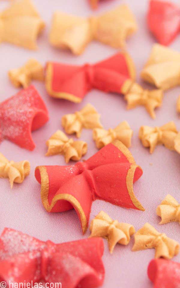 A close-up of a red bow painted with gold edible paint.