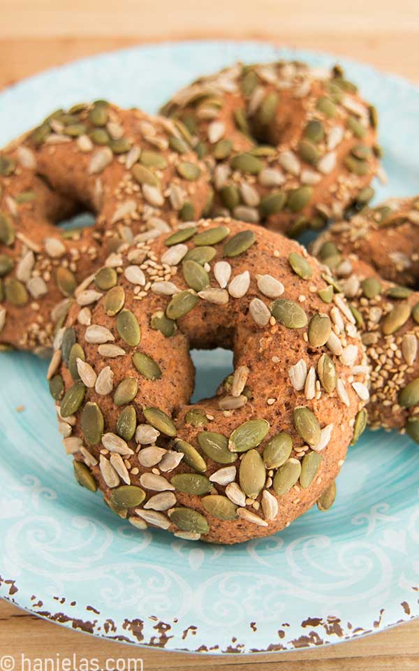 A light blue plate with baked bagel topped with seeds.