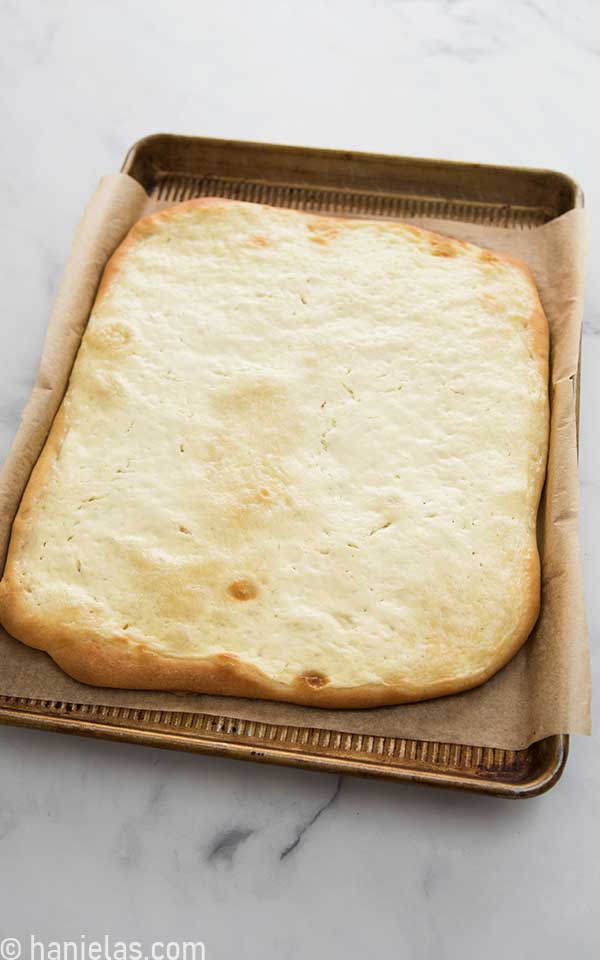 Baked bread with golden edges and white topping nested in a baking sheet with sides.