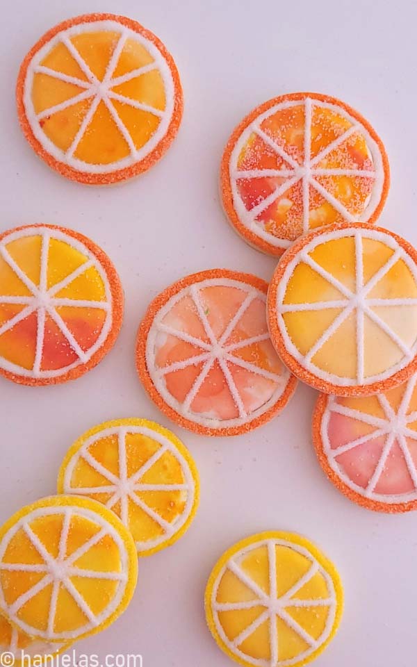 Round cookies that look like citrus slices, decorated with royal icing and edible paint.