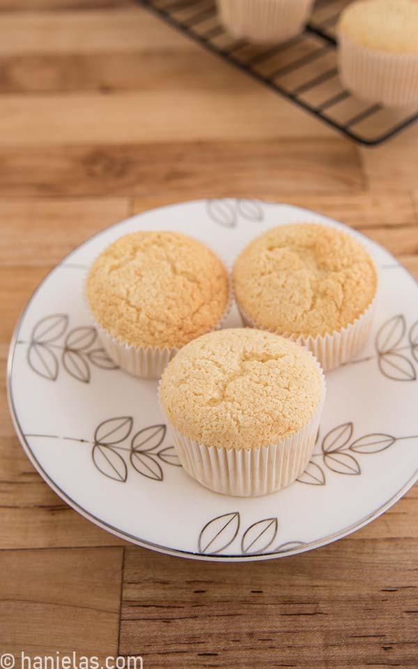 Three undecorated cupcakes on a white plate.
