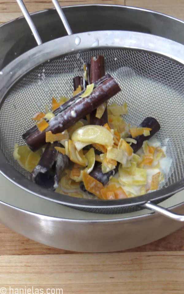 A mesh sieve with lemon, orange zest and cinnamon sticks.