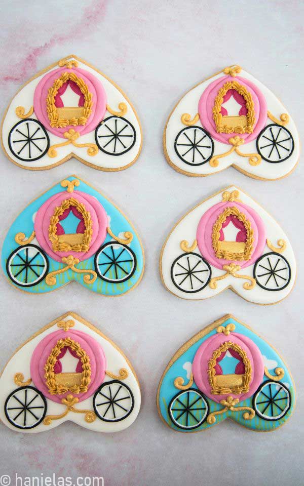 Six decorated cookies on a pink background.