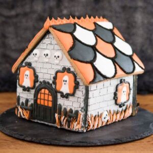 Gingerbread house decorated in black orange and white colors with cute ghost in the windows.
