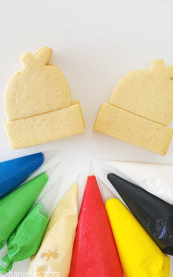 Baked cookies beside the piping bags filled with icing.