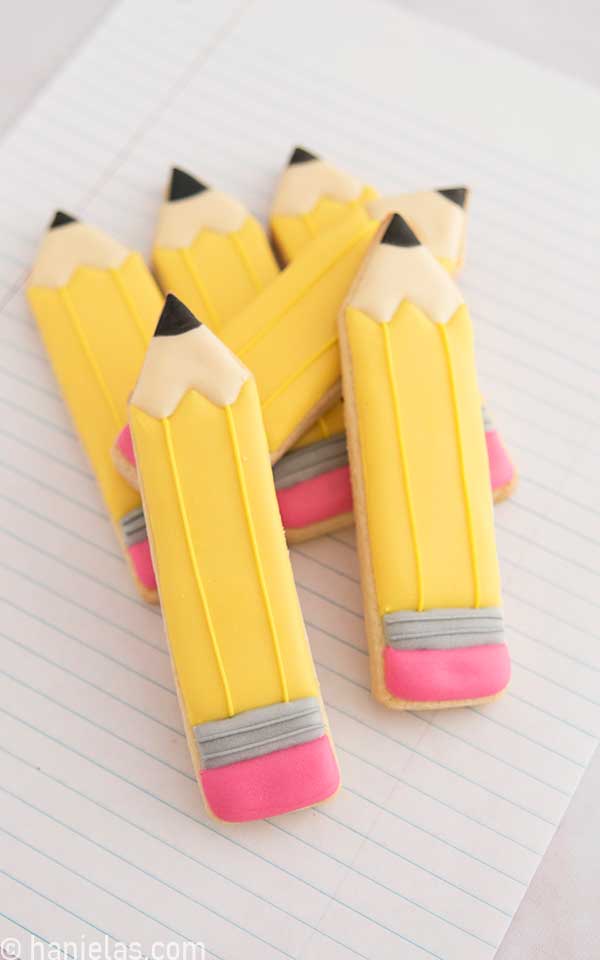 Stacked decorated pencil cookies on a lined paper.