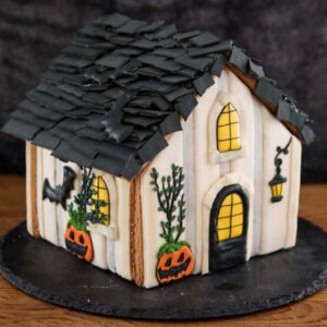 Cookie house decorated with royal icing, jack-o'-lanterns, bats.