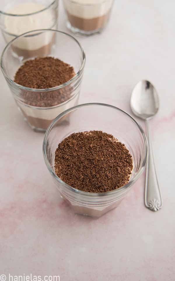 A view from above, two glasses filled with chocolate and vanilla layers, topped with grated chocolate.