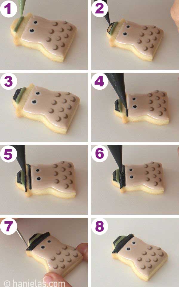 Piping a black hat with a green band onto a small snowman cookie.