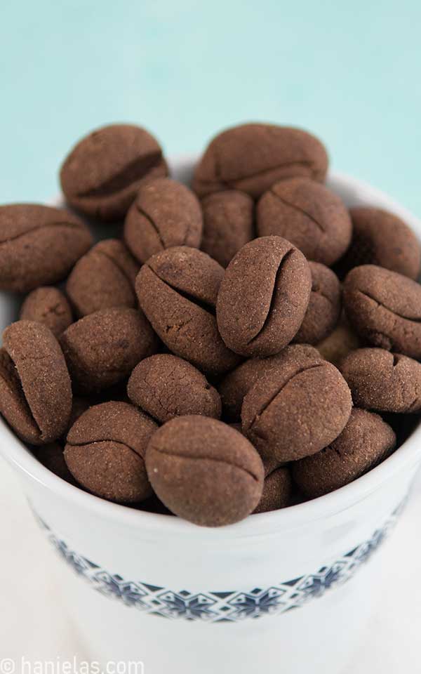 Cookies shapes like coffee beans in a white coffee mug with Scandinavian pattern.