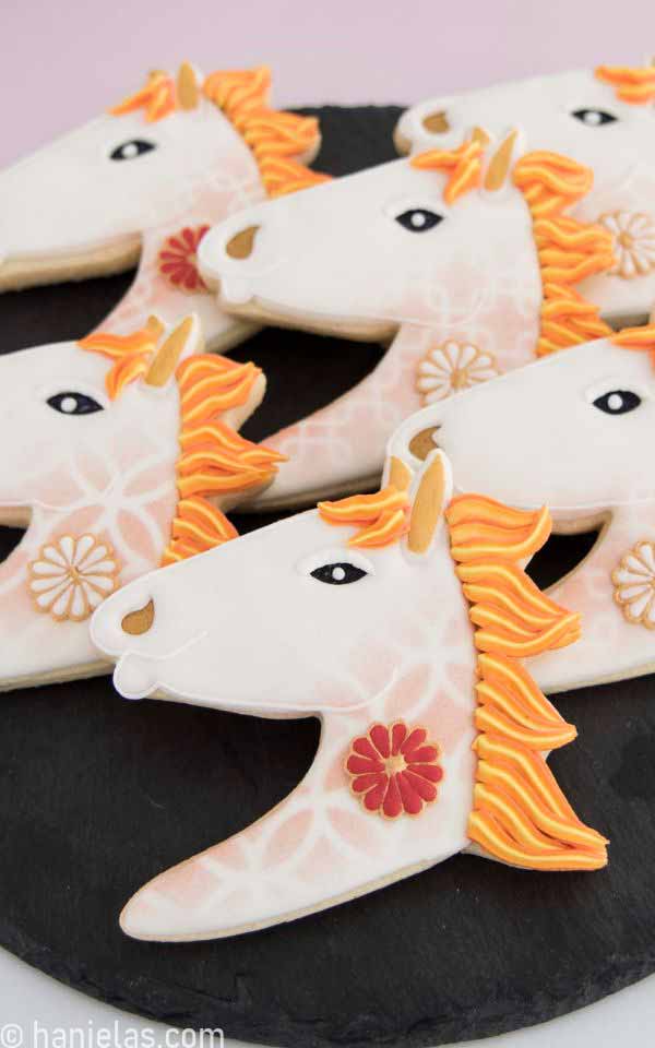 A closed up of decorated cookies on a black tray.