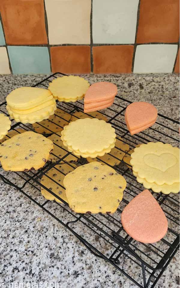 A variety of cut out cookies on a stacked cooling rack, on the kitchen countertop.
