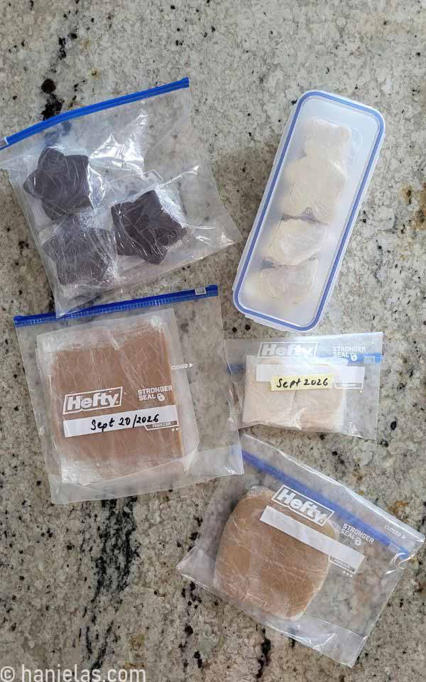 Container and ziploc bags filled with cut out cookies, cookie dough and rolled out cookie dough.